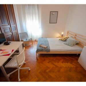 vista generale della stanza, compresa di letto matrimoniale, cassettiera e scrivania