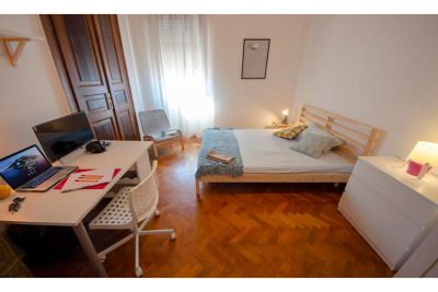 vista generale della stanza, compresa di letto matrimoniale, cassettiera e scrivania