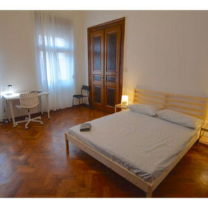 vista generale della stanza con letto matrimoniale e due finestre