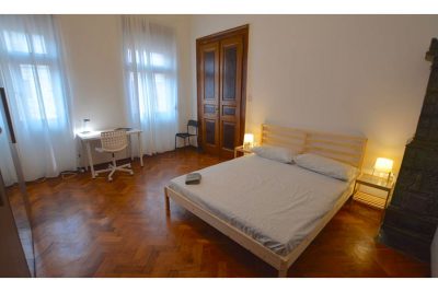 vista generale della stanza con letto matrimoniale e due finestre