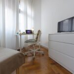 dettaglio della zona studio con scrivania, sedia, cassettiera e tv