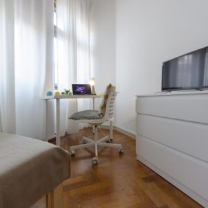 dettaglio della zona studio con scrivania, sedia, cassettiera e tv