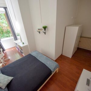 panoramica della stanza on letto matrimoniale a uso singolo, armadio, cassettiera, tv, zona studio e finestra sul verde