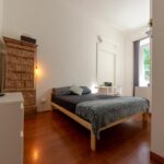 vista della stanza con letto matrimoniale, cassettiera, tv e mobile antico decorato