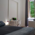 vista della stanza con letto matrimoniale, zona studio e finestra aperta