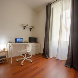 dettaglio della zona studio composta da scrivania, sedia, cassettiera e tv