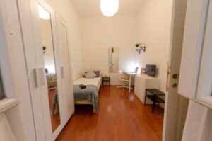 vista della stanza con letto singolo, armadio con specchio, zona studio, cassettiera e tv