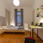 vista della stanza con letto, scrivania e sedia, comodino e lampada per studiare