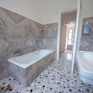 vista della stanza da bagno con vasca doccia e pavimento in terrazzo colorato