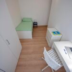 vista generale della stanza con scrivania, cassettiera, letto singolo e armadio