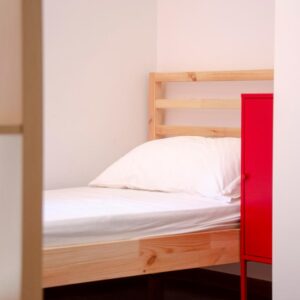 dettaglio del letto singolo con struttura in abete o comodino rosso a contrasto