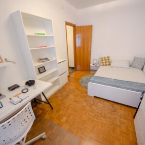 vista generale della stanza arredata con letto matrimoniale, libreria e zona studio lavoro