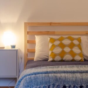 dettaglio del letto in legno di pino e del comodino con comoda lampada per letture